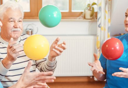 Eine Gruppe von Senioren und Betreuern in einem Pflegeheim spielen Ball