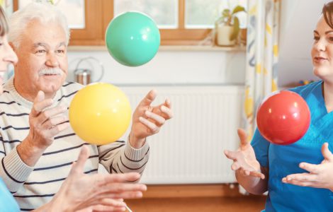 Eine Gruppe von Senioren und Betreuern in einem Pflegeheim spielen Ball